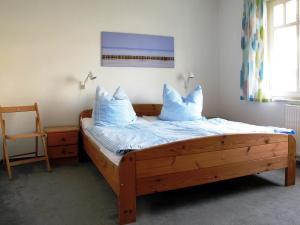 1 dormitorio con cama de madera con sábanas y almohadas azules en Ferienwohnung strandnah mit Balkon, en Ostseebad Koserow
