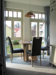 comedor con mesa, sillas y ventanas en Ferienwohnung strandnah mit Balkon, en Ostseebad Koserow