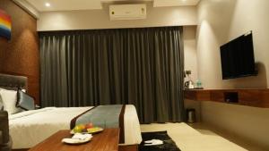 a hotel room with a bed and a television at Alaukik Hotel in Shirdi