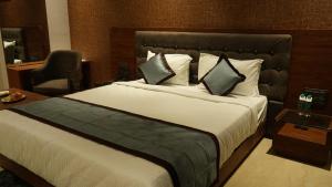 Habitación de hotel con cama grande y silla en Alaukik Hotel, en Shirdi