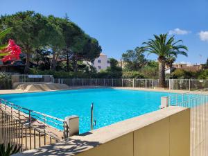 uma grande piscina azul com cerca e árvores em Miougrano 3 Pieces Climatise 48m2 5 Personnes Park em Fréjus