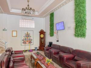 a living room with red leather couches and a clock at Nascar Family Hotel Palangkaraya Redpartner in Palangkaraya
