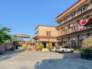 a building with two cars parked in a parking lot at Nascar Family Hotel Palangkaraya Redpartner in Palangkaraya