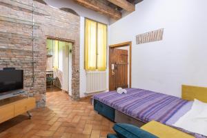a bedroom with a bed and a tv and a brick wall at De'Gombruti, Bologna by Short Holidays in Bologna