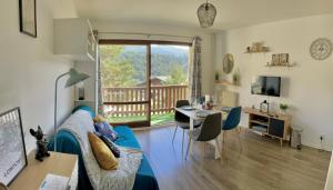 a living room with a blue couch and a table and a balcony at U066 - Appartement cosy, vue sur la montagne à Gréolières in Gréolières