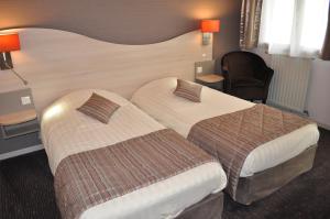 a hotel room with two beds and a chair at Logis Hotel au tambour in Reims