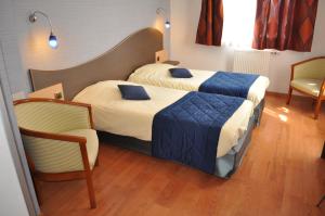 a hotel room with two beds and a chair at Logis Hotel au tambour in Reims +42 photos