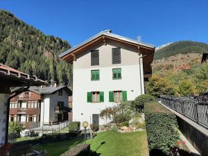 un edificio blanco con ventanas verdes y una colina en NUOVISSIMO BILOCALE PALAZZINA VENERI en Cogolo