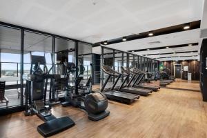 a gym with a row of treadmills and elliptical machines at Stunning Views 2BR Luxury Pool Parking Gym WiFi in Adelaide
