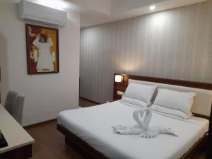 Un dormitorio con una cama con una toalla blanca. en Sai Maa Hotel & Residency, en Puttaparti