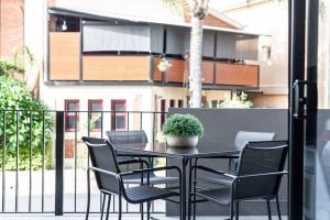 a black table with chairs and a potted plant on a balcony at Jewel on Jubilee - New 1 Bed Apt with Parking in Port Adelaide