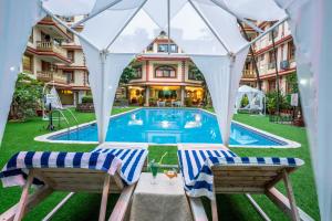 a swimming pool with two chairs and a house at Lillywoods Highland Beach Resort- Candolim in Candolim