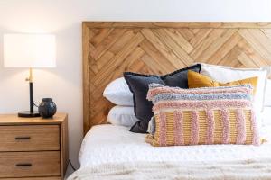 a bedroom with a bed with a wooden headboard and pillows at Jewel on Jubilee - New 1 Bed Apt with Parking in Port Adelaide