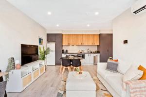 a living room with a white couch and a kitchen at Jewel on Jubilee - New 1 Bed Apt with Parking in Port Adelaide
