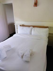 a white bed with white sheets and towels on it at Corofin Lake Cottages in Corrofin