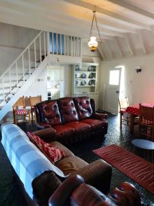 a living room with brown leather furniture and a staircase at Corofin Lake Cottages in Corrofin