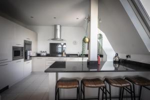 a kitchen with white cabinets and a counter with bar stools at Victorian Penthouse with panoramic sea views in Ilfracombe