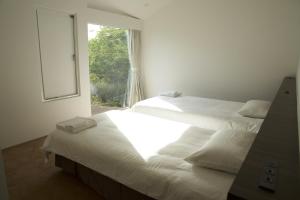 two beds in a white room with a window at Furano Peak in Furano