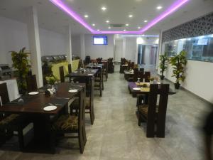 uma sala de jantar com mesas e cadeiras e luzes roxas em Pearl City Hotel em Colombo
