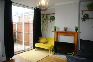 a living room with a yellow chair and a fireplace at Lovely 3 bedroom house with free parking & garden in Norwich