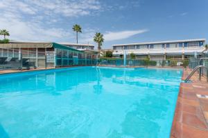 a large swimming pool with blue water at Barefoot Bungalow in Maspalomas