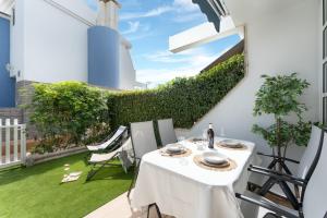a white table and chairs on a patio with grass at Barefoot Bungalow in Maspalomas