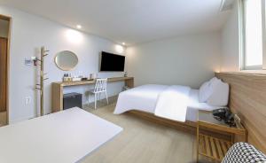 a bedroom with a bed and a desk with a television at Geoje Dongbeck Hotel Gohyeon in Geoje
