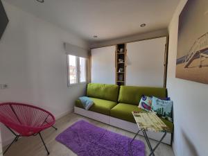 ブルゴスにあるApartamento Martinez del Campoのリビングルーム(緑のソファ、赤い椅子付)
