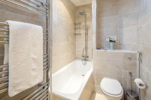 La salle de bains est pourvue d'une baignoire, de toilettes et d'un lavabo. dans l'établissement ALTIDO 2-bed flat near Notting Hill, à Londres