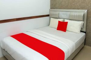 1 dormitorio con cama blanca y almohada roja en Zazadior Residence Syariah near Pantai Padang Mitra RedDoorz en Padang