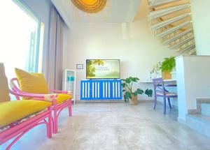 ein Wohnzimmer mit bunten Stühlen und einem TV in der Unterkunft La Casa de las Hespérides in Morro del Jable