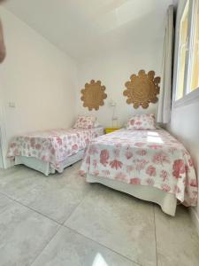 una camera con due letti con lenzuola rosa di La Casa de las Hespérides a Morro del Jable