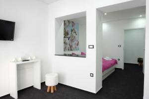 Una habitación blanca con una cama y un espejo. en Luwiana Suites, en Liubliana