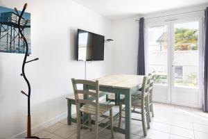 uma sala de jantar com uma mesa e cadeiras e uma televisão em Appartement Colombelle proche du marché et de la plage em La Couarde-sur-Mer
