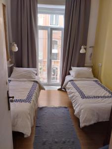 two beds in a room with a window at Edith Cavell10 Lisbon Guest House in Lisbon