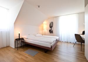 a white bedroom with a large bed and a desk at Hotel Sonne Sissach in Sissach