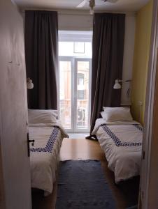 two beds in a room with a window at Edith Cavell10 Lisbon Guest House in Lisbon