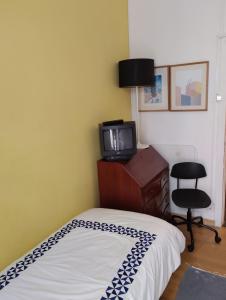 a bedroom with a bed and a tv and a chair at Edith Cavell10 Lisbon Guest House in Lisbon