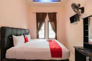 RedDoorz Syariah at D'Ostha Residence في بوكيتينجى: غرفة نوم بسرير كبير ونافذة