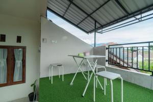 Cette chambre dispose d'un balcon avec une table et des chaises. dans l'établissement RedDoorz Syariah at D'Ostha Residence, à Bukittinggi