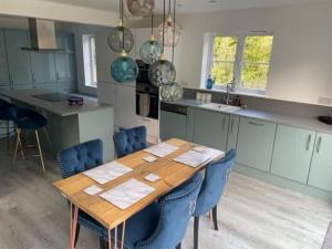 uma cozinha com uma mesa de madeira e cadeiras azuis em Large 5 Bedroom Family home with parking and WI-FI em Kettering