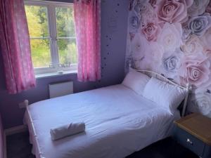 a bedroom with a bed with roses on the wall at Large 5 Bedroom Family home with parking and WI-FI in Kettering