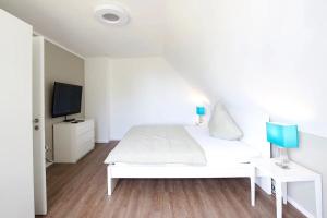 a white bedroom with a white bed and a tv at Naturferienhaus 1 in Mellnitz