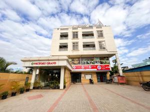 een hoog wit gebouw met een bord ervoor bij Victory Grand Attibele in Bangalore