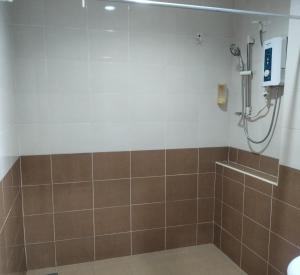 La salle de bains est pourvue d'une douche et de carrelage brun. dans l'établissement Reintree Lodge Hotel, à Ipoh