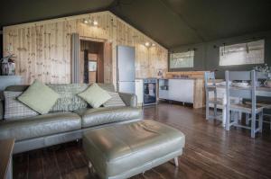 a living room with a couch and a kitchen at Worms Head - Safari Tent - Llangennith in Llangennith +33 photos