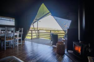 a living room with a fireplace and a view of the ocean at Worms Head - Safari Tent - Llangennith in Llangennith
