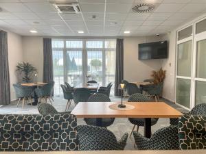 a conference room with tables and chairs and a flat screen tv at Gyirmót Sport & Wellness Hotel in Győr