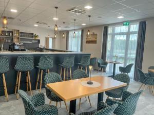 a restaurant with chairs and tables and a counter at Gyirmót Sport & Wellness Hotel in Győr