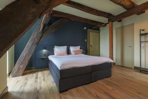 a bedroom with a large bed with blue walls and wooden floors at Hotel Corps de Garde in Groningen